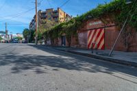 a empty street next to several tall brick buildings with green vines on it's side