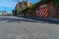 a empty street next to several tall brick buildings with green vines on it's side