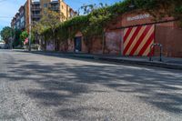 a empty street next to several tall brick buildings with green vines on it's side