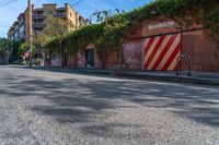 a empty street next to several tall brick buildings with green vines on it's side