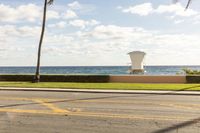 a lifeguard chair that is on the grass and beside the ocean with some palm trees