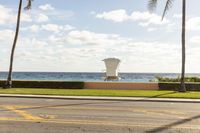 a lifeguard chair that is on the grass and beside the ocean with some palm trees