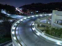 a city view at night shows a freeway going over the cliff tops and light up buildings