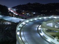 a city view at night shows a freeway going over the cliff tops and light up buildings