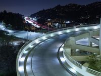 a city view at night shows a freeway going over the cliff tops and light up buildings