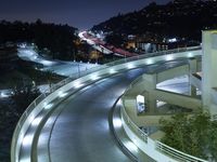 a city view at night shows a freeway going over the cliff tops and light up buildings