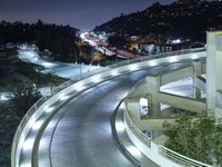 a city view at night shows a freeway going over the cliff tops and light up buildings