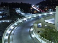 a city view at night shows a freeway going over the cliff tops and light up buildings