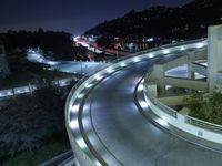 a city view at night shows a freeway going over the cliff tops and light up buildings