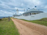 the pathway leads to a lighthouse at cape town in australia with white fences and grass