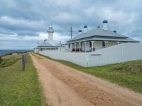 the pathway leads to a lighthouse at cape town in australia with white fences and grass