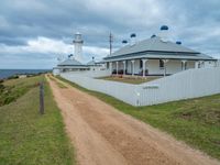 the pathway leads to a lighthouse at cape town in australia with white fences and grass