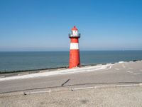 a lighthouse is built in concrete overlooking the ocean shore and blue sky a clear day