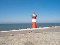 a lighthouse is built in concrete overlooking the ocean shore and blue sky a clear day