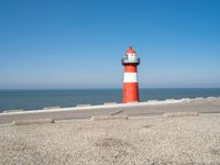 a lighthouse is built in concrete overlooking the ocean shore and blue sky a clear day