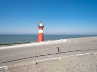 a lighthouse is built in concrete overlooking the ocean shore and blue sky a clear day