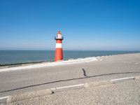 a lighthouse is built in concrete overlooking the ocean shore and blue sky a clear day