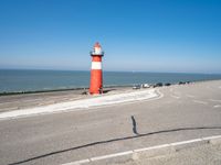 a lighthouse is built in concrete overlooking the ocean shore and blue sky a clear day