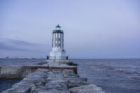 there is a lighthouse on the side of the rock wall by the water, and the light house is also near a dock