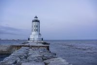 there is a lighthouse on the side of the rock wall by the water, and the light house is also near a dock