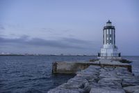 there is a lighthouse on the side of the rock wall by the water, and the light house is also near a dock