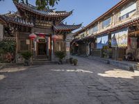 a city street with asian buildings and flags on it is empty and quiet with sunlight casting shade