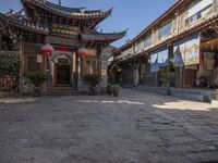 a city street with asian buildings and flags on it is empty and quiet with sunlight casting shade