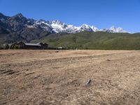 a field with a couple of horses in it with mountains in the background near some snow capped peaks