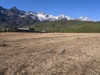 a field with a couple of horses in it with mountains in the background near some snow capped peaks