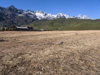 a field with a couple of horses in it with mountains in the background near some snow capped peaks