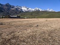 a field with a couple of horses in it with mountains in the background near some snow capped peaks