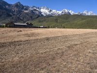 a field with a couple of horses in it with mountains in the background near some snow capped peaks