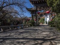 lanterns stand on the end of an archway leading to some chinese buildings in a park