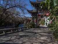 lanterns stand on the end of an archway leading to some chinese buildings in a park