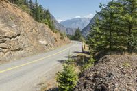 the mountains surrounding a road that is steep and full of dirt and pine trees along its sides