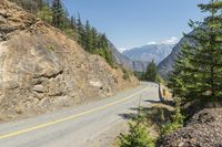 the mountains surrounding a road that is steep and full of dirt and pine trees along its sides