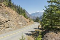 the mountains surrounding a road that is steep and full of dirt and pine trees along its sides