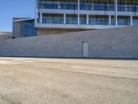 an older man is skateboarding down a slope outside of a large building while the sun shines down on him