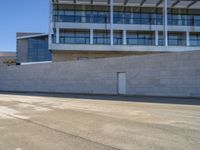 an older man is skateboarding down a slope outside of a large building while the sun shines down on him