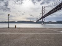 the view of a bridge from across the water to a beach, with a large island in