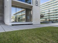 an empty walkway leads to the entrance of a building on which the exterior is glass