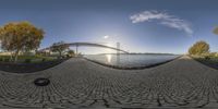 a wide angle view of a bridge in the distance and a path by a body of water