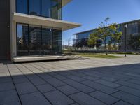 a square building sitting in the middle of an empty courtyard with trees and some buildings