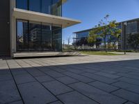 a square building sitting in the middle of an empty courtyard with trees and some buildings