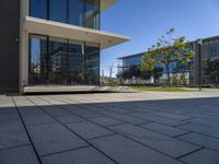 a square building sitting in the middle of an empty courtyard with trees and some buildings