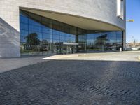 the view of the exterior of a building with reflective windows and stone pavement in front