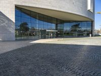 the view of the exterior of a building with reflective windows and stone pavement in front