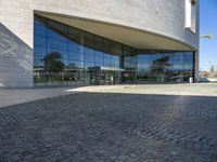 the view of the exterior of a building with reflective windows and stone pavement in front