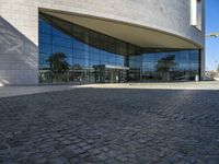 the view of the exterior of a building with reflective windows and stone pavement in front