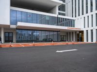 a large building that has a glass facade and lots of orange cones in front of it